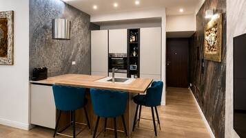 Eine moderne Küche mit Backofen und einer Essecke mit Holztisch und blauen Stühlen.