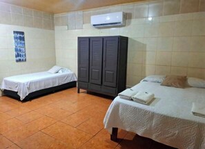 A room with two beds, a wardrobe, and an air conditioning unit.