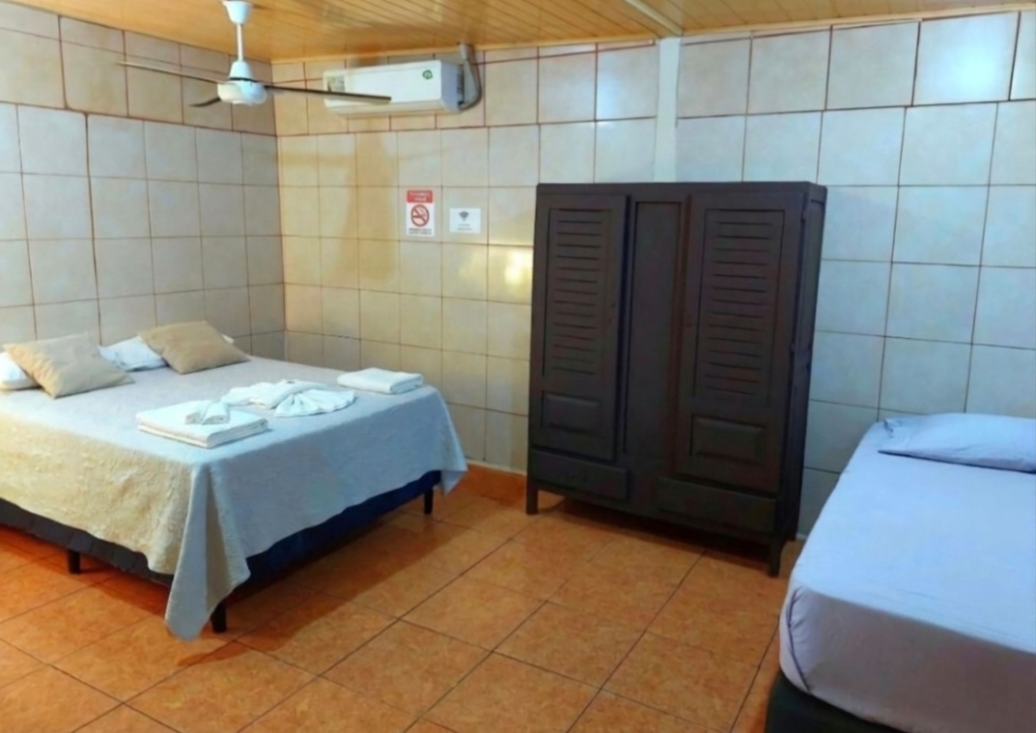 Une chambre d’hôtel équipée d’un lit, d’une armoire, d’un ventilateur de plafond et d’un appareil de climatisation.
