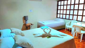 A hotel room with a bed, a desk, a chair, and a window with blinds.