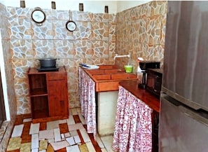 Una cocina compacta con refrigerador, estufa y un pequeño armario de madera.