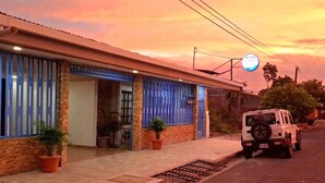 Un edificio con fachada azul, un vehículo estacionado y cielo despejado.