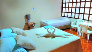 Habitación de hotel con cama, escritorio, silla y ventana con persianas.