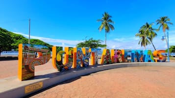 A sign with colorful letters spelling 'PUNTARENAS' and a mural with tropical scenes.