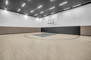 A basketball court with a hoop, a wooden floor, and a ceiling with linear lighting fixtures. - Modern 1BR | Pool & Gym Access | Downtown Miami (Miami)