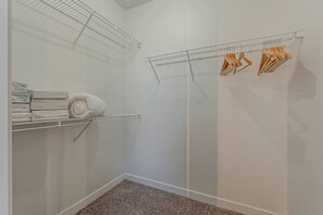 A small, enclosed room with a shower, a metal drying rack, and a stack of folded towels.
