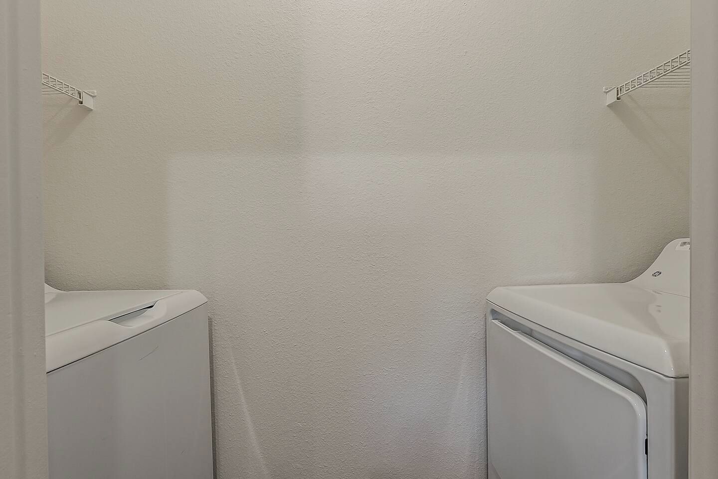 Een wasserette met twee witte wasmachines en een witte muur.