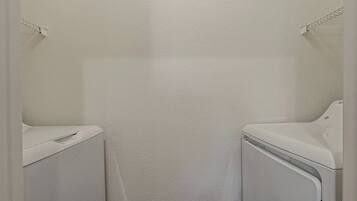 Een wasserette met twee witte wasmachines en een witte muur.