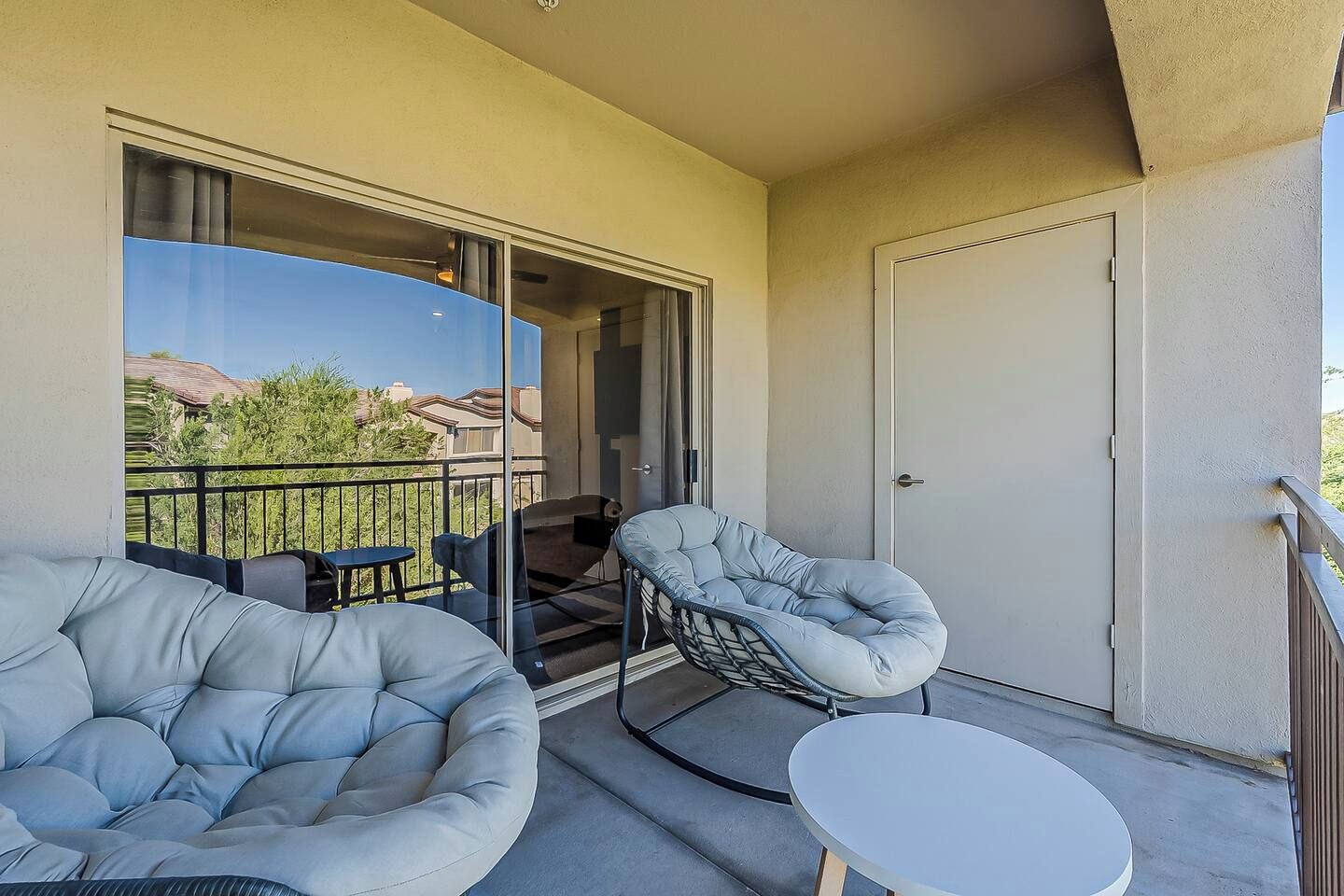 Ein Balkon mit einer Couch, einem Sessel und einem kleinen Tisch.