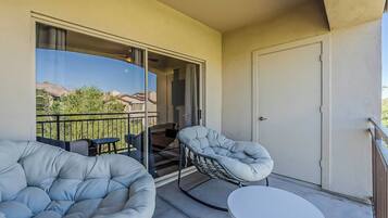 Ein Balkon mit einer Couch, einem Sessel und einem kleinen Tisch.