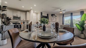 Un espace repas moderne avec une table ronde prévue pour quatre personnes, entourée de fauteuils en cuir.