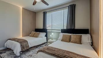 Habitación de hotel con dos camas, ventilador de techo, ventana con persianas y lámpara de noche.