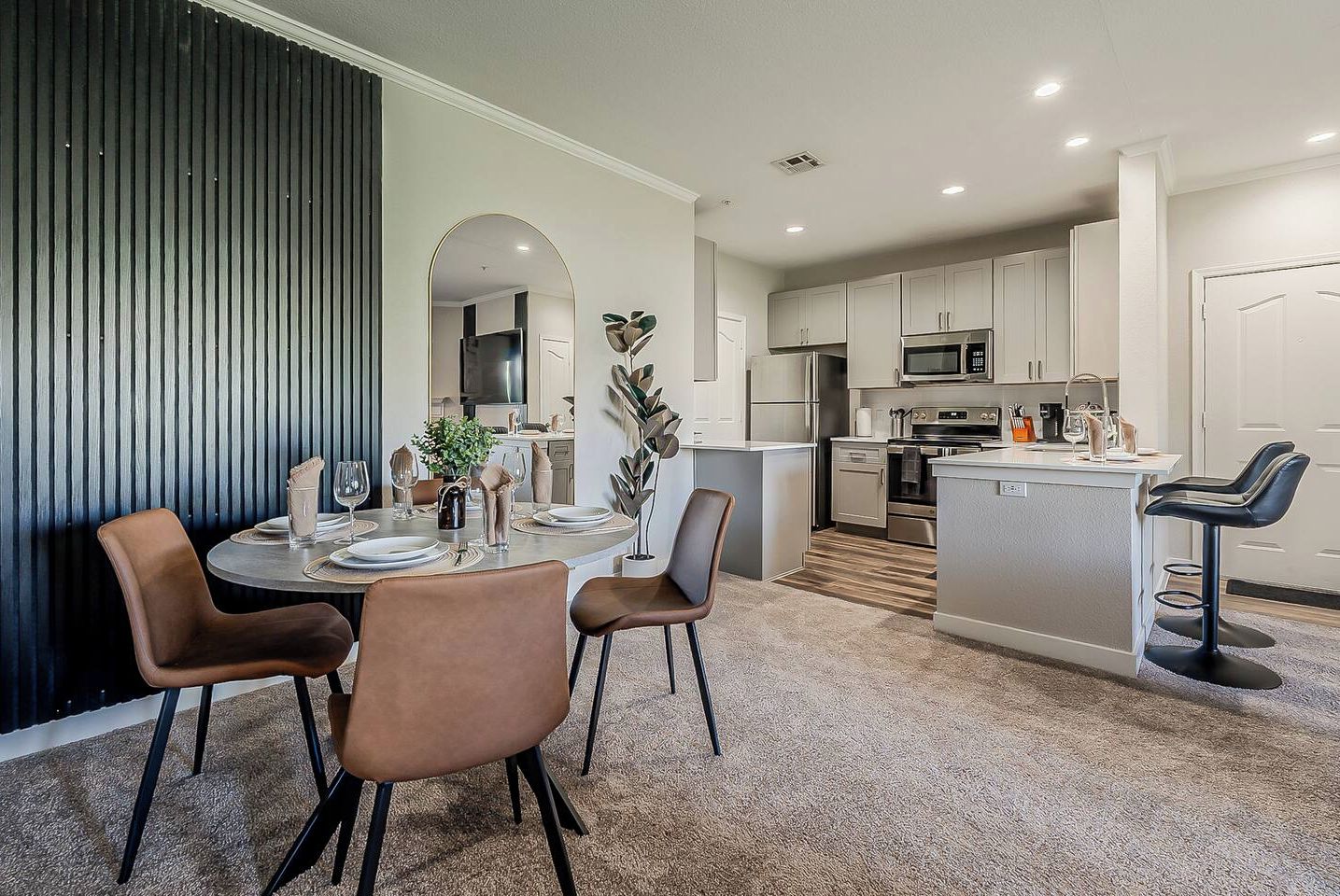 Una cocina moderna con armarios blancos, una isla central y un comedor con una mesa redonda y sillas.
