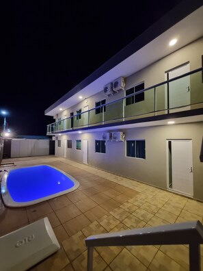 Un immeuble de deux étages doté d’une piscine, de balcons et d’une entrée sécurisée par un portail.