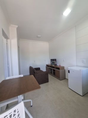 Un espacio habitable compacto con kitchenette, una mesa de comedor, un sofá y un refrigerador.