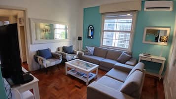 A living room with a sofa, armchairs, a coffee table, and a television.