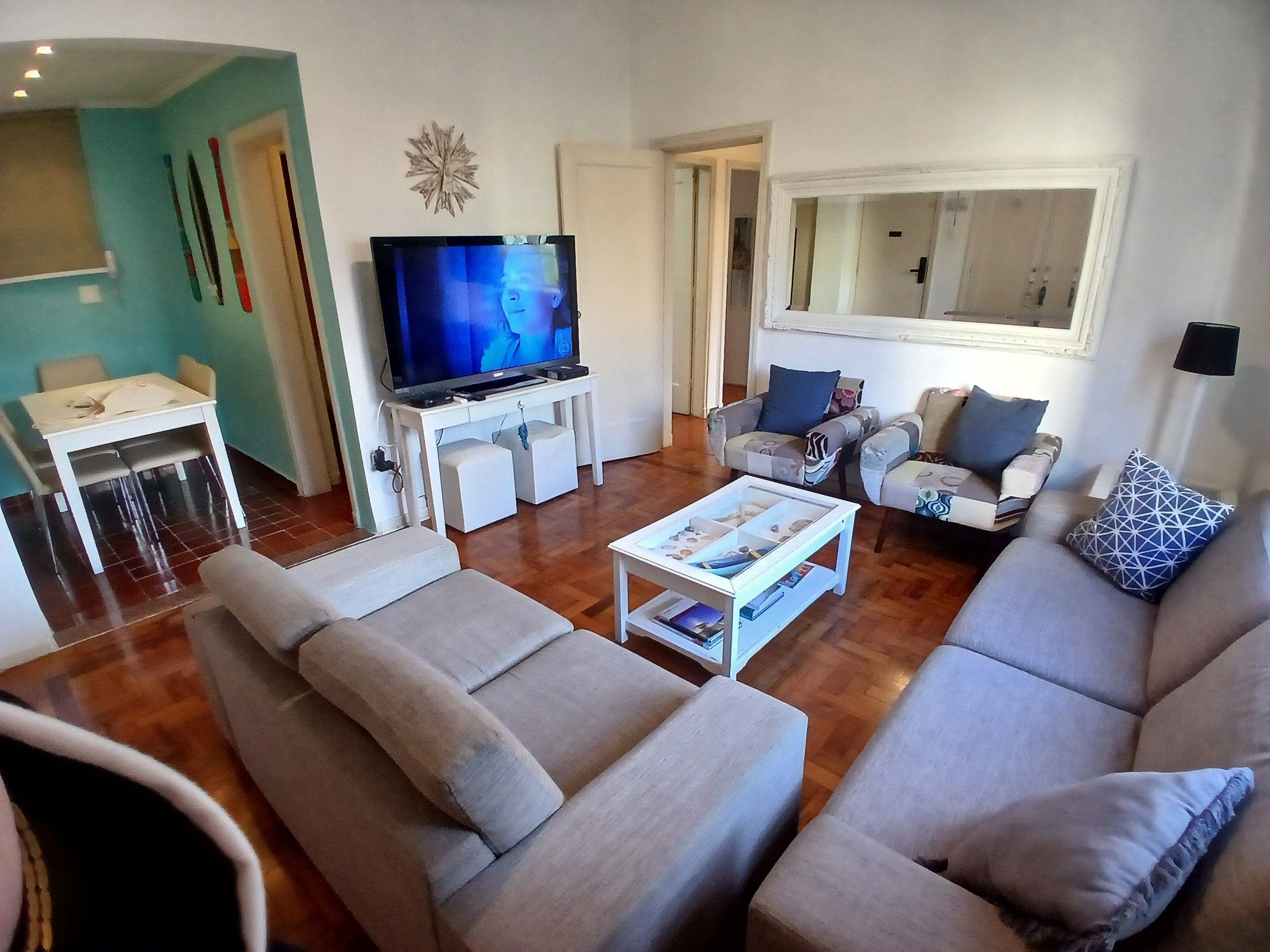Una sala de estar con sofá, sillones, una mesa de centro, televisión y un comedor con sillas y mesa.