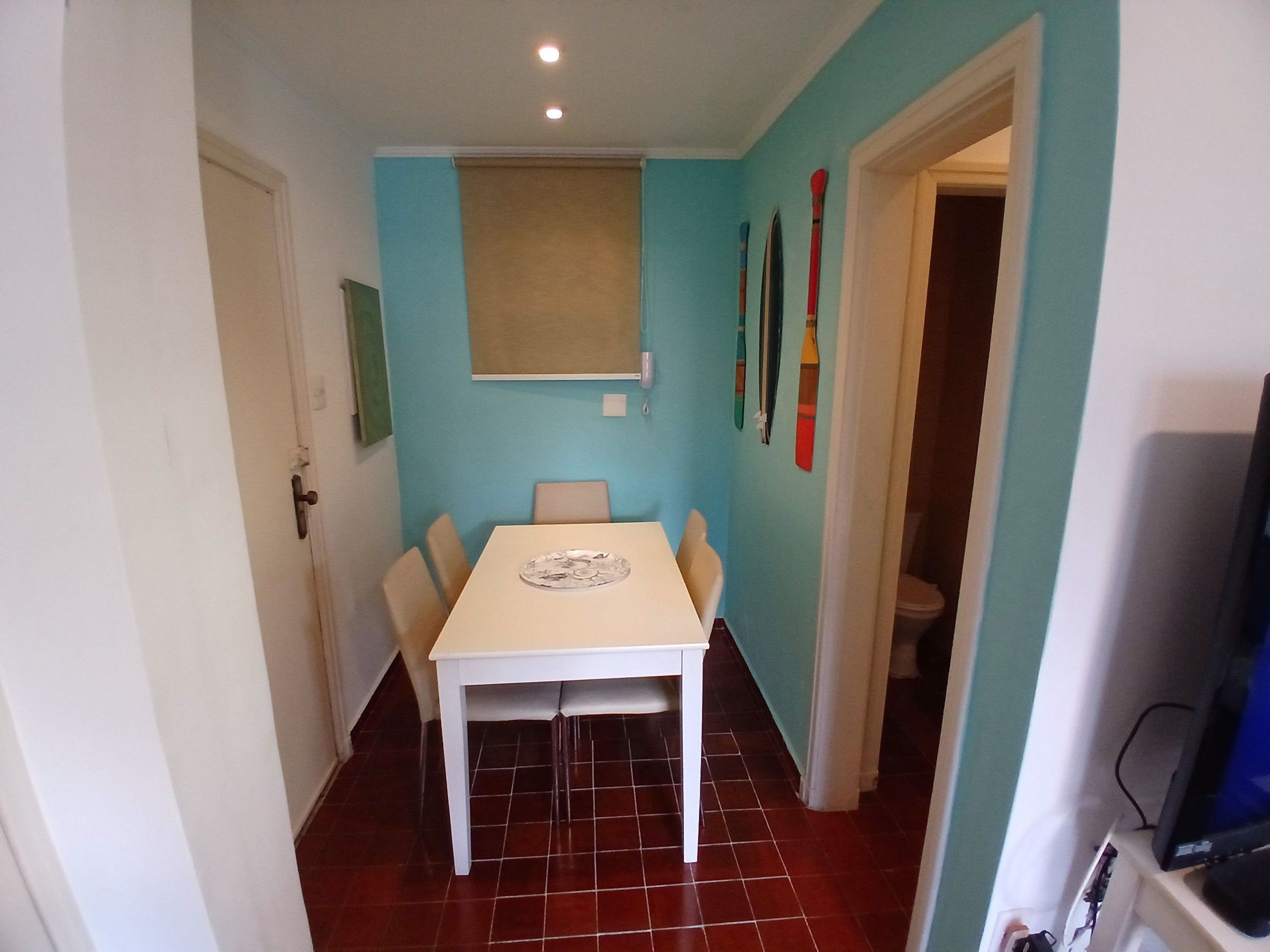 Un couloir étroit avec une table et des chaises, une fenêtre et une porte donnant sur une salle de bain.