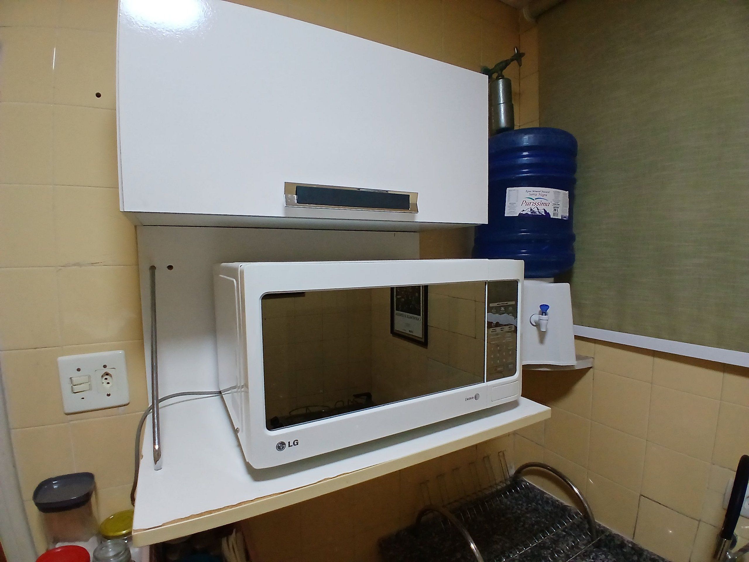 A kitchen with a microwave, a water dispenser, and a water cooler.