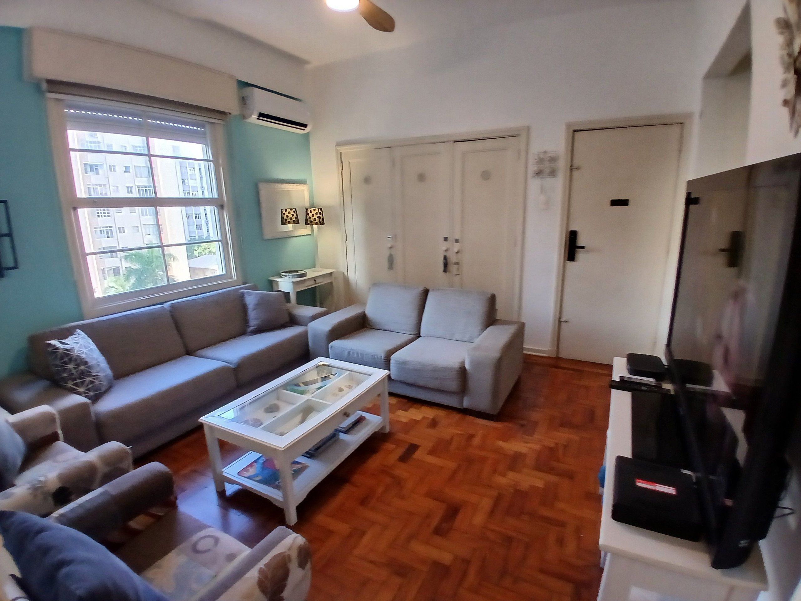 A living room with a sofa, armchair, coffee table, and TV stand.