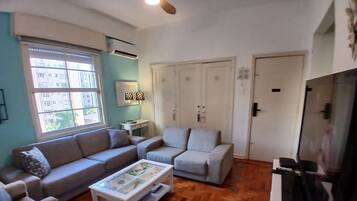 A living room with a sofa, armchair, coffee table, and TV stand.
