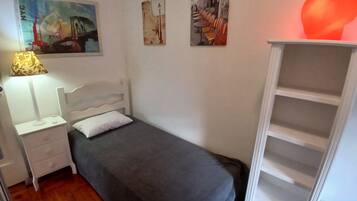 A bedroom with a bed, a nightstand, a lamp, a wardrobe, and wall art.