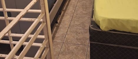 A room with bunk beds, a single bed, a door leading to a balcony, and a tiled floor.