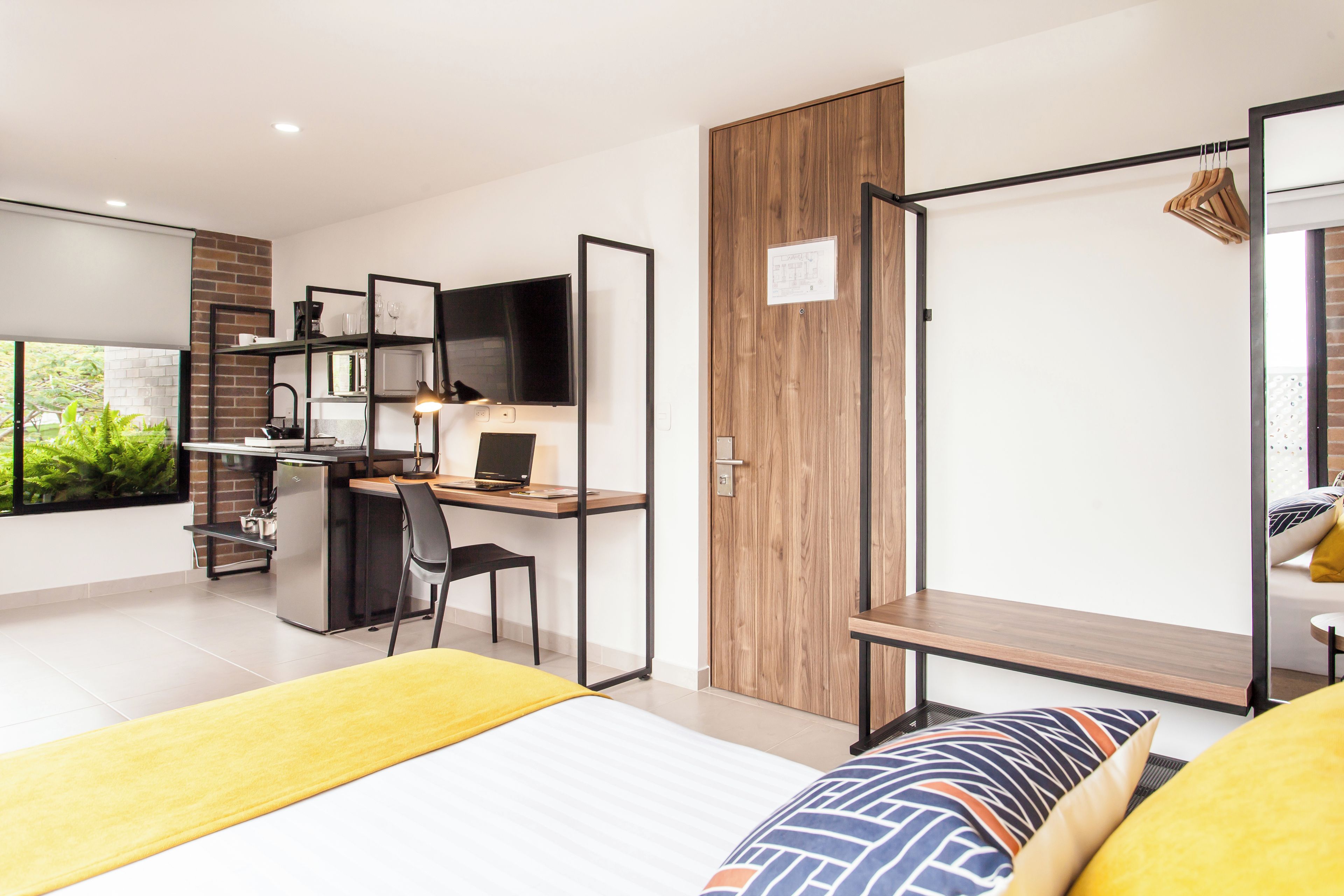 A modern bedroom with a bed, a desk, and a wardrobe.