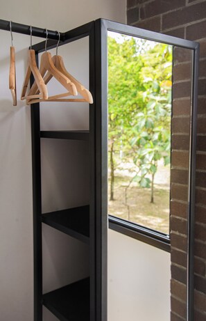 Une étagère en métal noir avec des supports en bois, et une fenêtre donnant sur un paysage verdoyant.