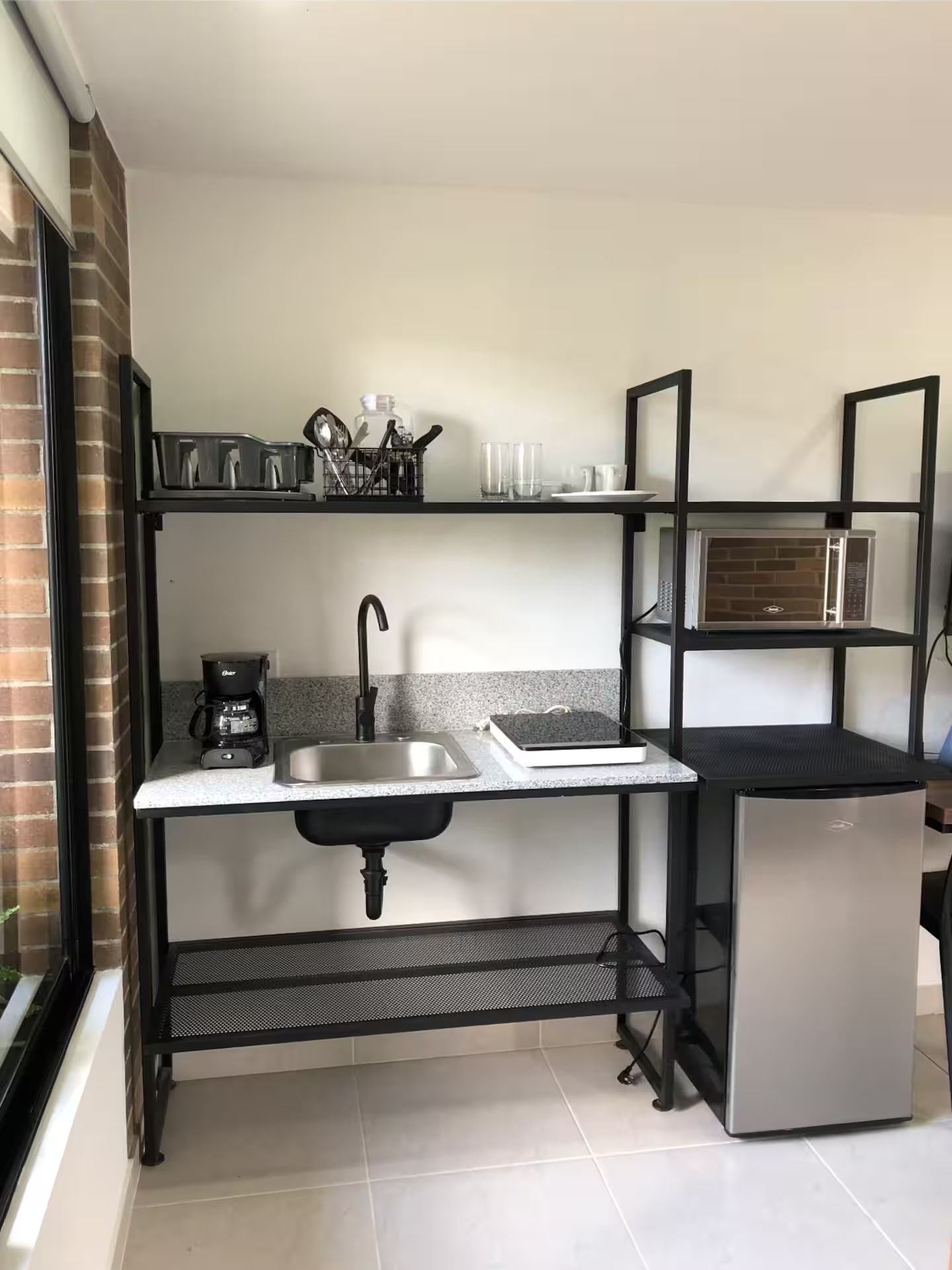 A compact kitchen with a sink, a coffee maker, a microwave, and a small refrigerator.