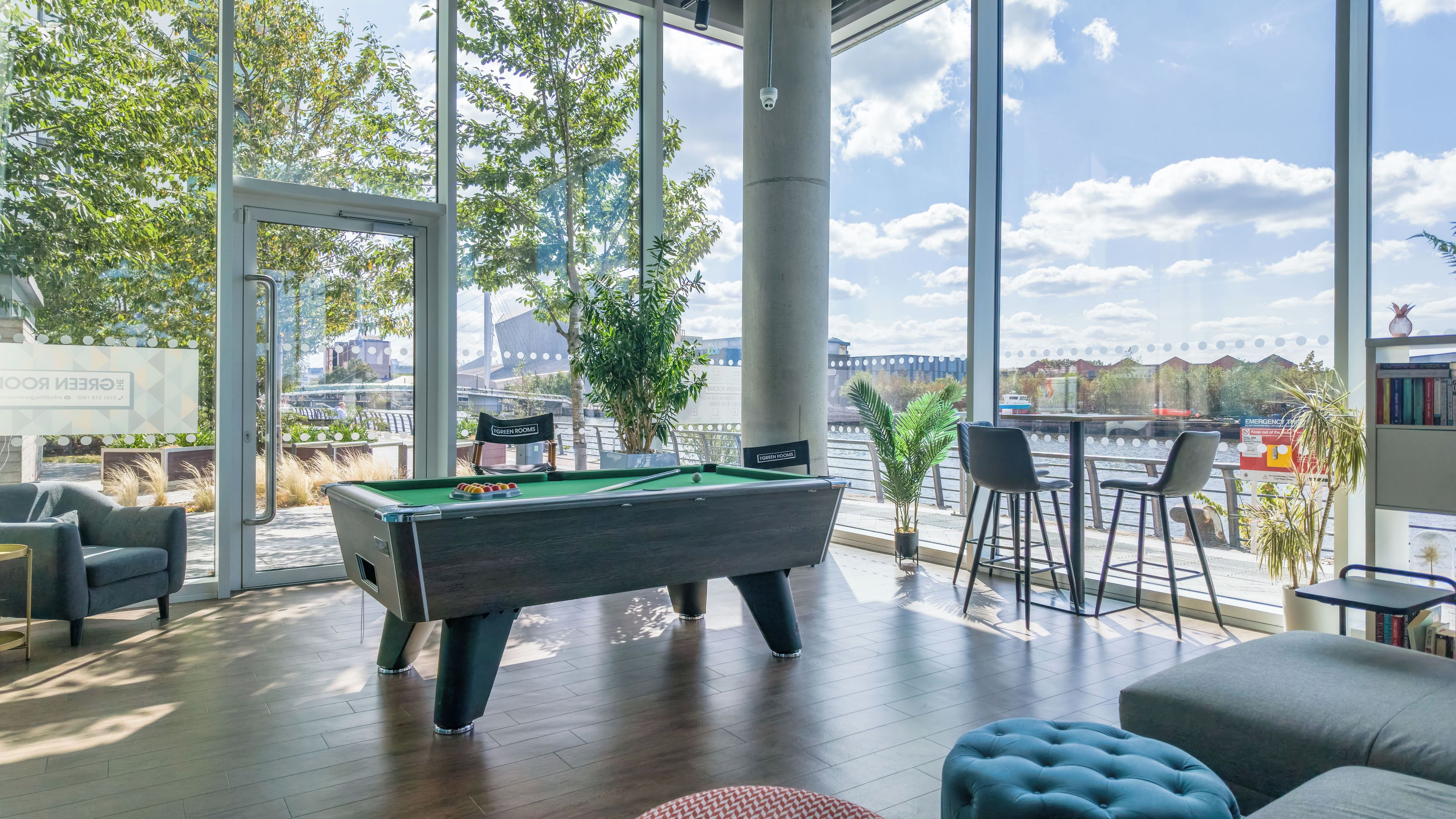 A pool table in a room with large windows, a bar area, and a view of a river.