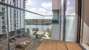A high-rise building with a view of a river and a parking area below. - Green Rooms by Veeve (Salford)