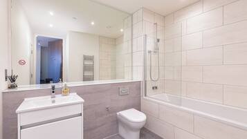 Une salle de bain moderne avec une douche à parois de verre, des toilettes blanches et un meuble-lavabo avec un miroir.