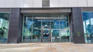 A modern building entrance with glass doors and windows, labeled 'EGREEN ROOMS' with a sign indicating no smoking. - Green Rooms by Veeve (Salford)