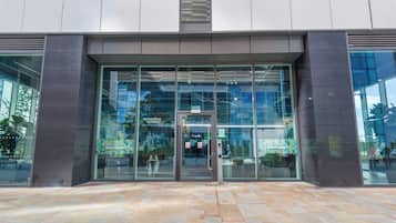 A modern building entrance with glass doors and windows, labeled 'EGREEN ROOMS.'