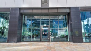 Entrada d'un edifici modern amb portes i finestres de vidre, amb la inscripció 'EGREEN ROOMS' i un senyalitzador que indica que no es pot fumar.