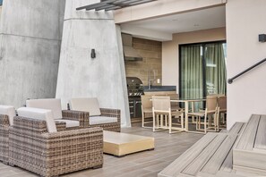 A modern outdoor patio with wicker furniture, a dining table, and a kitchen area with a grill. - 4BR house with hot tub near Disney area (Kissimmee)