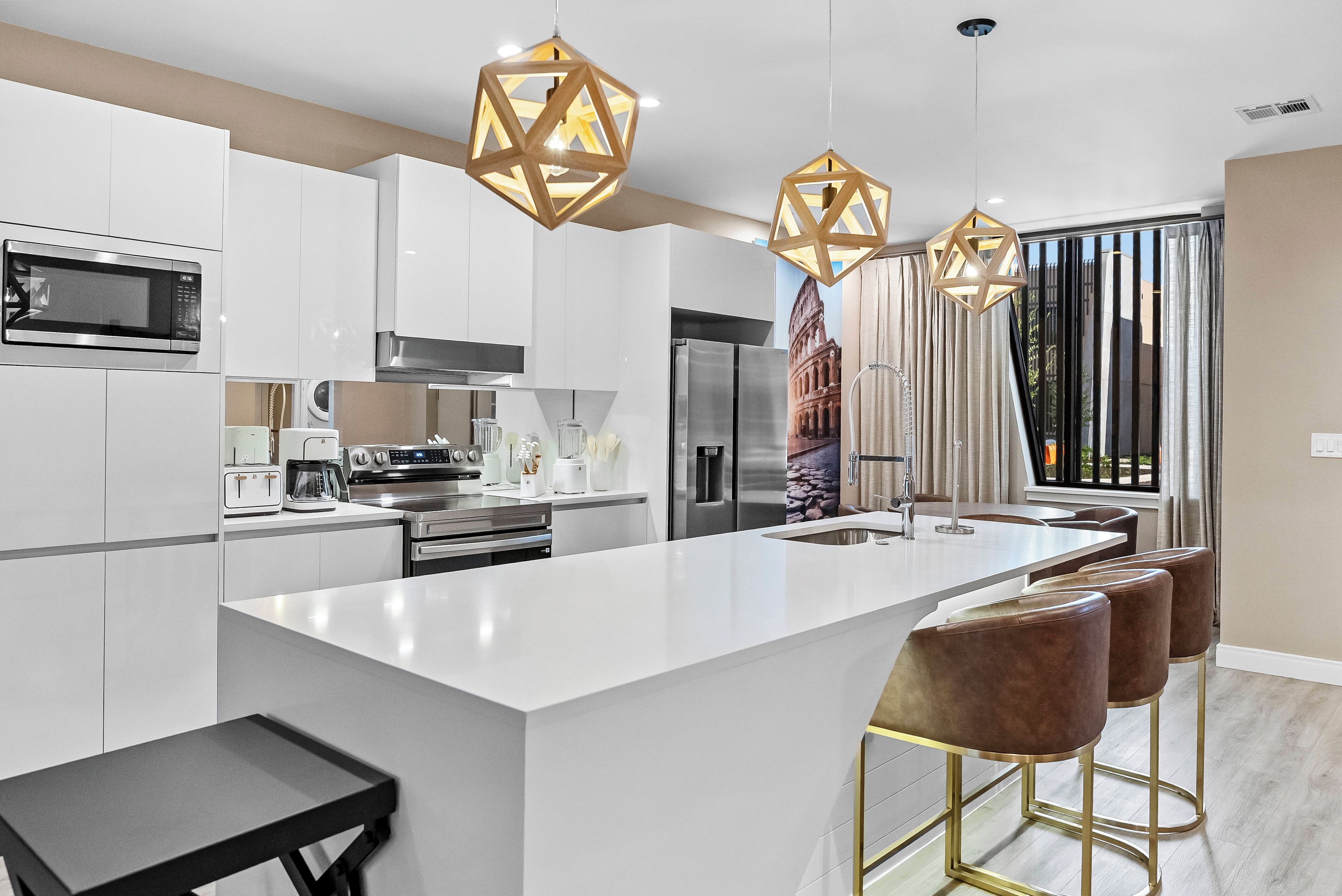 Una cocina moderna con una isla central, electrodomésticos de acero inoxidable e iluminación colgante.
