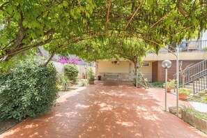 A covered outdoor area with a tiled walkway, surrounded by greenery and potted plants. - Villa Muse by BarbarHouse (Leporano)