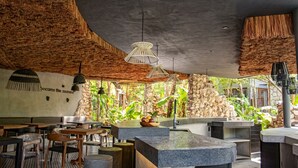 Een restaurant met een rustieke inrichting, met stenen muren, houten meubels en hangende lampen.