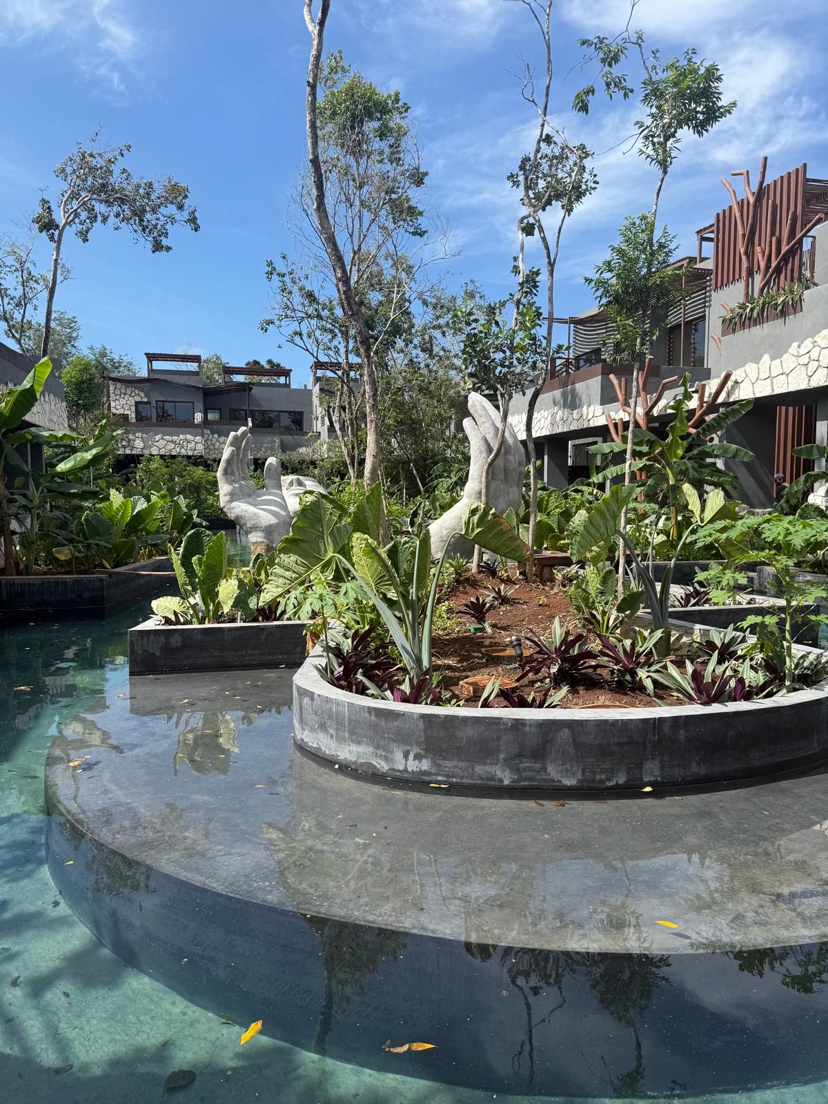 A swimming pool with clear water, surrounded by lush greenery and modern architecture.