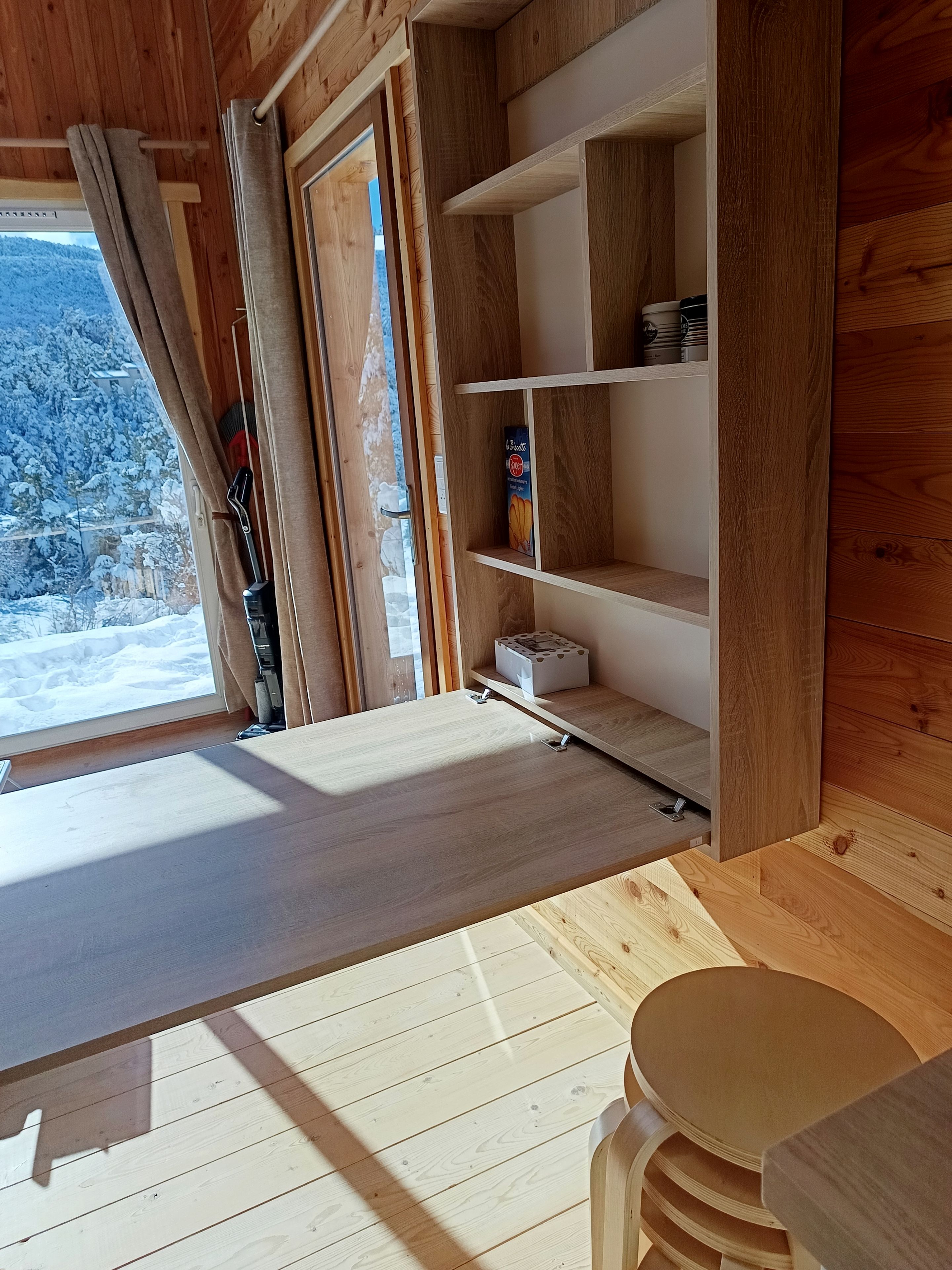 Un interior de madera con una ventana, estanterías y una mesa.