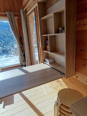 Un interior de madera con una ventana, estanterías y una mesa.