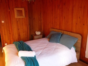 A wooden-paneled room with a bed, pillows, and a nightstand. - L'ânon d'Andon (Andon)