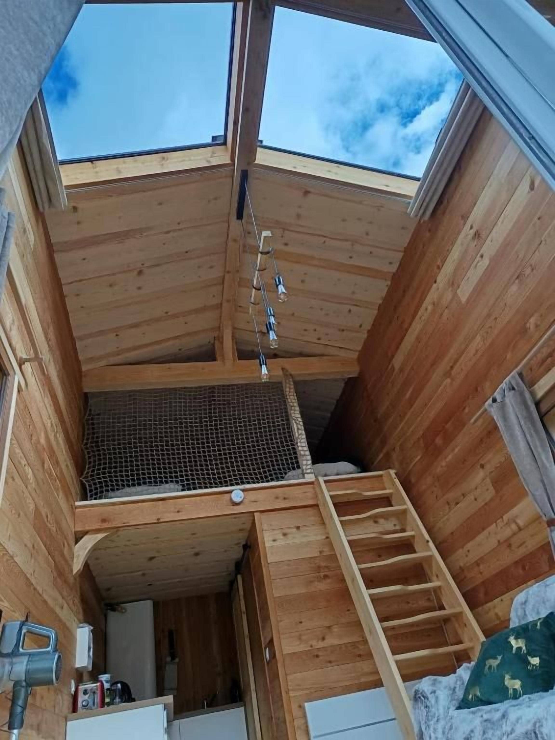 Un interno in legno con finestra a lucernario, una scala e una piccola area chiusa con tetto a rete.