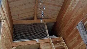 Un interno in legno con finestra a lucernario, una scala e una piccola area chiusa con tetto a rete.