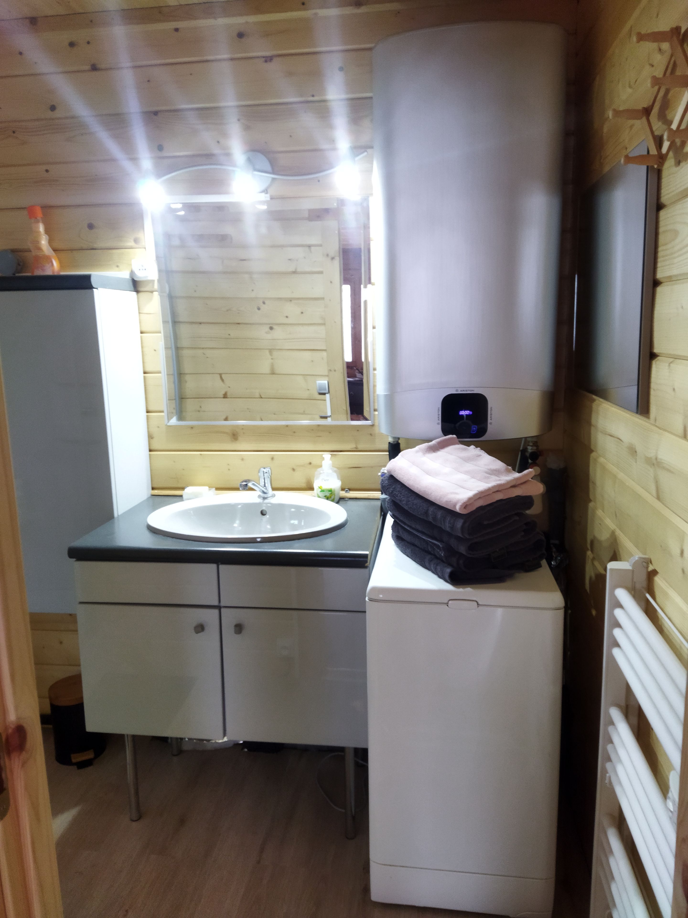 A compact bathroom with a sink, mirror, and a small white cabinet.