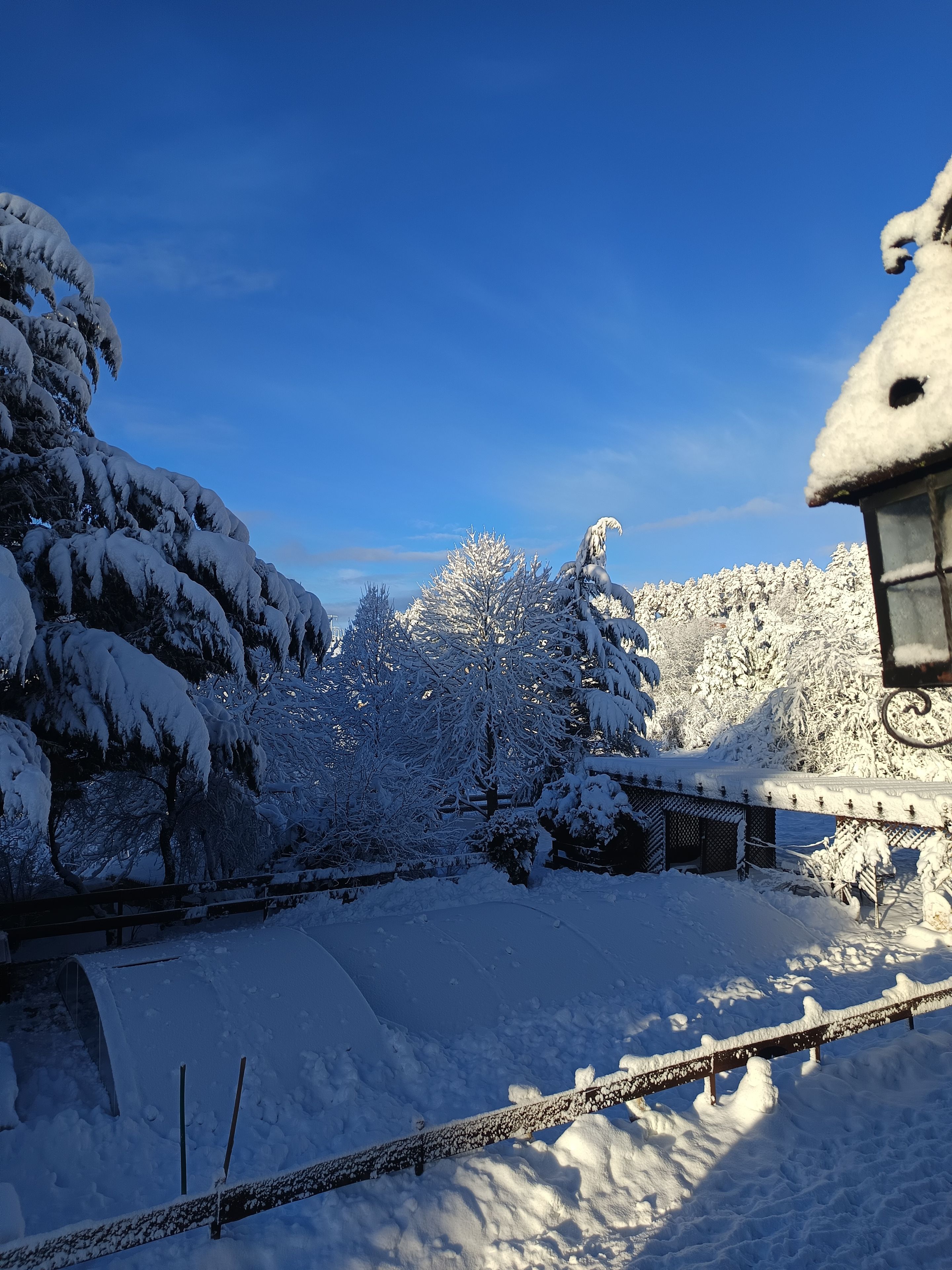 Un paisaje nevado con una valla de madera y un edificio con tejado cubierto de nieve.