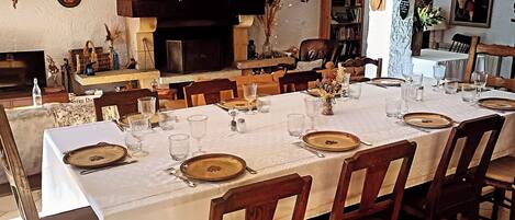 A dining area with a long table set for a meal, surrounded by chairs.