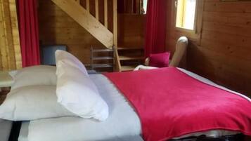 Een houten cabinneerinrichting met een bed, een stoel, een trap en een raam.